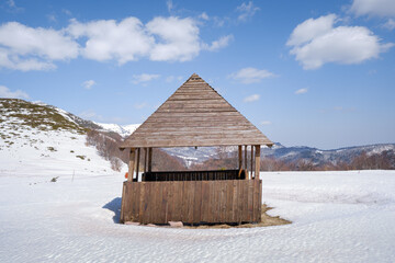 Wooden mountain summer house leaning from the wind on snow covered highland - 549267325