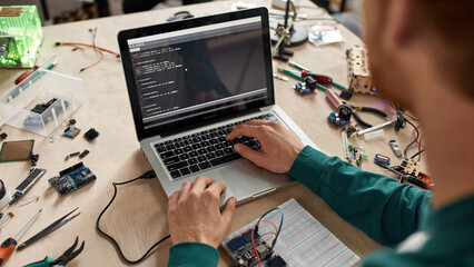 Cropped IT engineer programming code of microchip