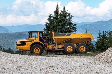 A big yellow construction truck in the mountains 