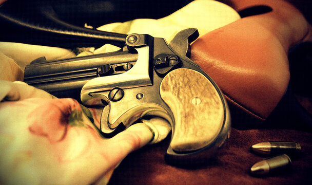 A double barrel derringer style pistol with high heels and a nighty in sepia tones. This kind of weapon was used by gamblers and women in the past because of its small