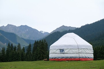 Yurt camp in Karakol Mountains, Tien Shan Mountains, Kyrgyzstan, Central Asia. Traditional nomad's yurt on green mountain meadow in summer. 