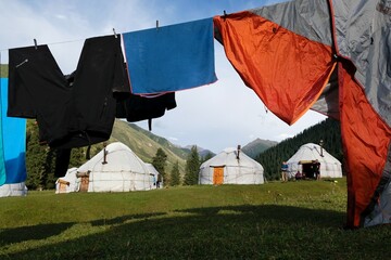Yurt camp and clothes drying on lines in front of yurts. Traditional nomad's yurts on beautiful mountain meadows in the green Tien Shan Mountains in Karakol area in the summer. Kyrgyzstan