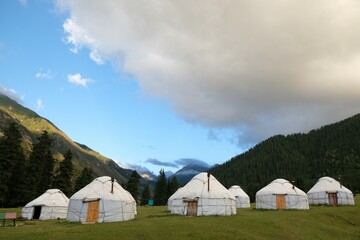 Fototapeta na wymiar Yurt camp in Karakol Mountains, Tien Shan Mountains, Kyrgyzstan, Central Asia. Traditional nomad's yurts on green mountain meadow in summer. 