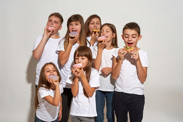 Group of caucasian children eating sweet doughnuts