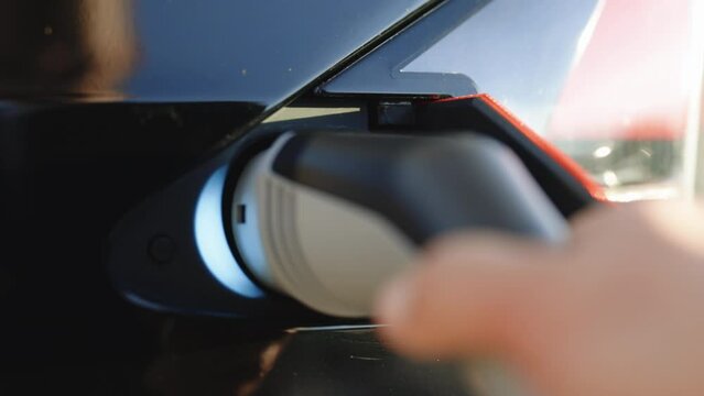 Tesla model X S Plaid charge port opening and plugging in supercharger cable. Opening charging port. Hand plugging in electric car, modern electric car.