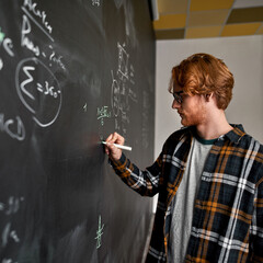 Smart man writing math formula on blackboard