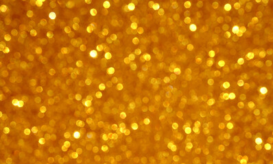 Blurred glitter background in golden color as a part of Christmas design.Holiday abstract texture with bokeh lights.Fabric sequins.