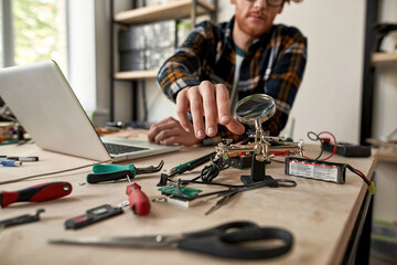 Partial male IT technician taking magnifying glass