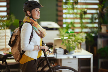 smiling elegant business woman in bike helmet in eco office