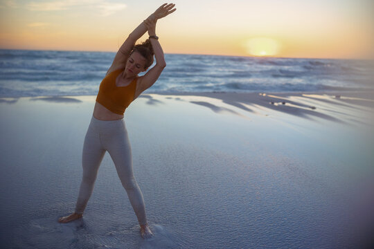 healthy sports woman at beach in evening stretching