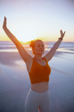 active woman jogger at beach at sunset rejoicing