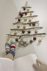 a man is resting with a book on the background of a handmade Christmas tree
