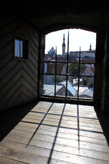 old European city with houses and churches through the open door of the fortress wall with iron lattice