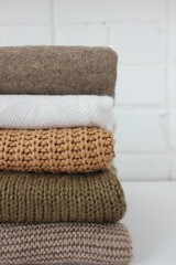 beige, brown and wite knitted sweaters neatly folded in stack