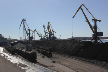 mountains of coal and silhouettes of cranes on in Port