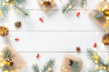 Christmas background with eco-packed gifts, blue fir branches and festive bokeh on a white wooden background