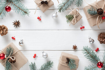 Christmas background with eco-packed gifts, blue fir branches and festive bokeh on a white wooden background.
