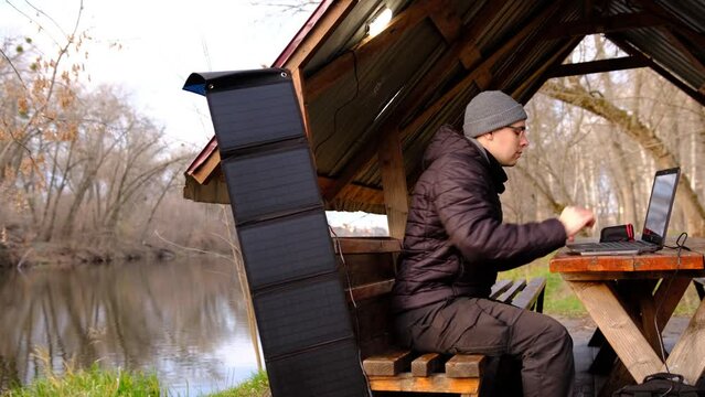 Man work on laptop charginf from portable solar 