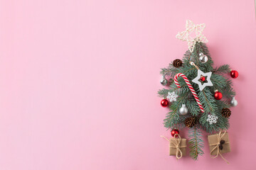 Creative Christmas tree with Christmas decorations on a pink background with a place for textiles. Minimalism in the concept of Christmas and New Year
