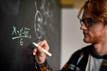 Man writing technical formula with marker on board