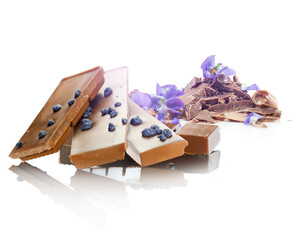 Kawałki czekolady o smaku fiołków, z fiołkami na białym jednolitym tle.  - obrazy, fototapety, plakaty