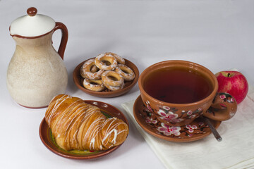 a cup of tea with a croissant on the table with a white tablecloth