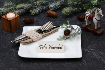 Mesa navideña festiva con platos y cubiertos. Felicitación navideña en una tarjeta de sitio....