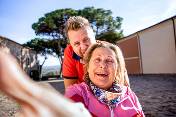 Fototapeta premium Disabled woman on wheelchair taking selfie with man at park - Happy family having fun together outdoors - Son and mother trying to take a crazy picture - Focus on woman