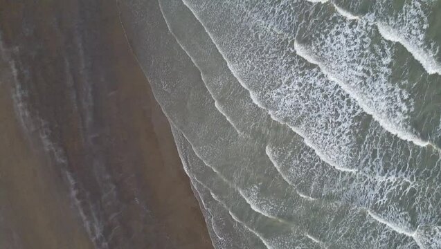 Aerial shot of Eraclea beach with sand, waves and stones, Veneto