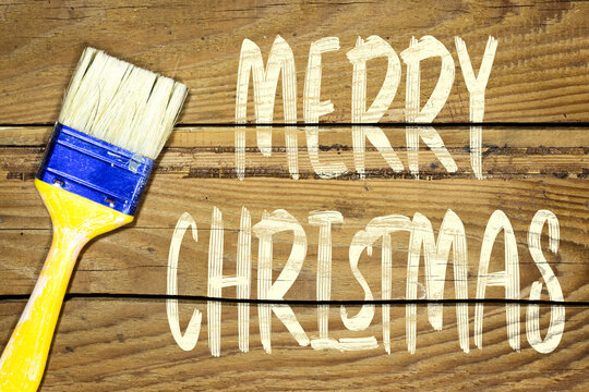 paint brush and painting merry christmas  on wooden background. holiday concept