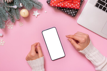 Obraz premium Phone mock up and female hand with Christmas New Year work table decoration top view, flat lay on pink background