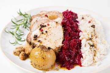 Roast pork loin slices served with basmati rice and fried beets with roasted onions and garlic, decorated with rosemary 