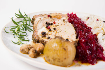 Roast pork loin slices served with basmati rice and fried beets with roasted onions and garlic, decorated with rosemary 