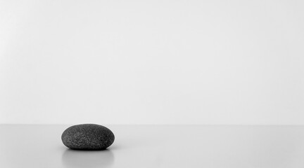 Black oval stone on white table. Concept harmony, balance. Selective focus. Copy space.