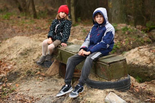 Childen sitting on military surplus ammo box, russian invasion to Ukraine