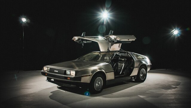 Vintage DMC DeLorean model with the doors up, isolated on dark background with studio lights
