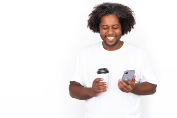 Portrait of cheerful mid adult man holding smartphone and coffee against white background. African American man using mobile phone and laughing. Mobile communication concept