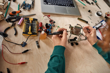 Partial male engineer soldering microchip at table