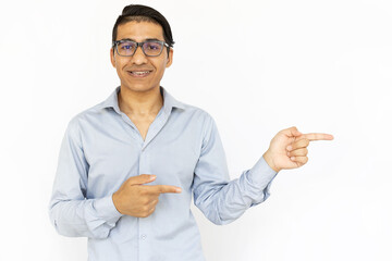 Smiling man pointing aside. Indian man in blue shirt presenting product or app. Portrait, studio shot, advertising concept
