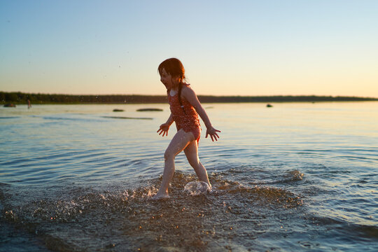 Little girl plays in the sea in summer, splashes with water.