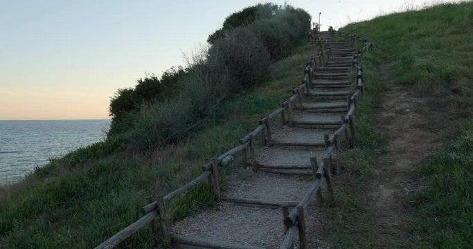 Stairs at sunset with wooden handrails on a hill near the Aegean Sea in Greece