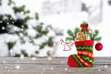 Christmas boot of Santa Claus with pine branches, gingerbread and toys on a winter background.