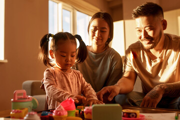 Smiling mother and father look at daughter play