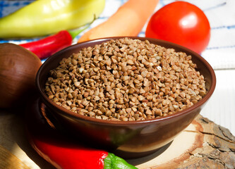 Buckwheat in a bowl, red pepper, carrots and onions on the board.