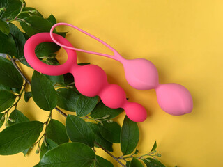 Sex toys. Pink butt plug and geisha balls on a yellow background. Useful for sex shop, adults