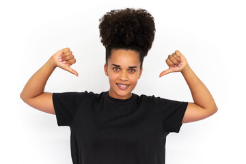 Portrait of confident young woman poiting thumbs at herself against white background. African...