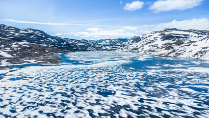 Aerial view a frozen lake with melting ice on a lake in the mountains in Norway