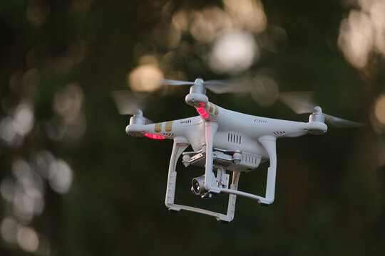 15 - Selective focus side view of hovering remote control drone. Copy space in the left side portion of the frame. Modern technology in action