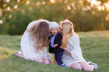 A young beautiful blonde mother walks and rests with her baby son in the park at sunset in good weather