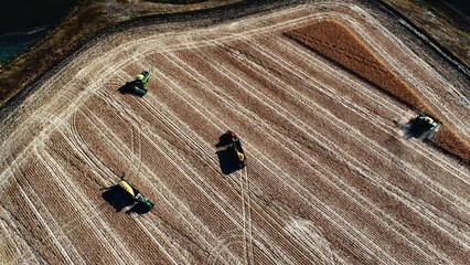 Agricultural photo of autumn harvest. View from a drone. Tractors at work. Harvesting corn.